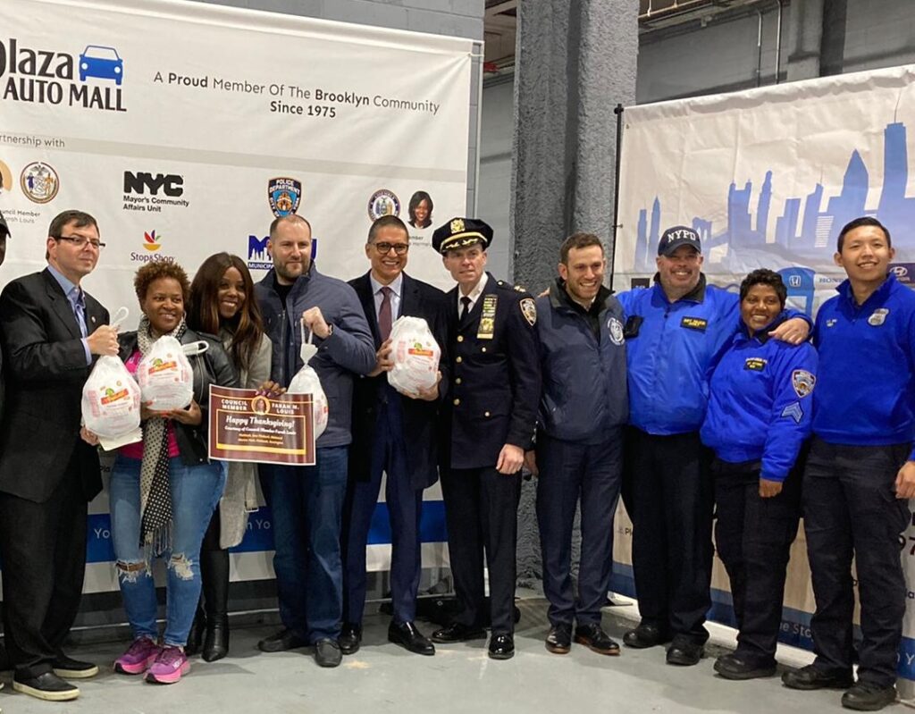 Group shot of Turkey Giveaway. From left to right: Fred Kreizman, Commissioner of Community Affairs Unity, Mayor's Office; Assemblymember Nikki Lucas; Council Member Farah N. Louis; Adam Rosatti, CEO of Plaza Auto Mall; Sean Tahzib, Marketing Director for Plaza Auto Mall; Charles McEvoy, Chief of Brooklyn Borough South of NYPD; Ido Shargal, Queens Borough Director of Community Affairs Unity for the Mayor's Office; Scott Nuzzi, Detective for 70th Precinct Community Affairs, NYPD; Natasha Moseley, P.O. for 70th Precinct Community Affairs, NYPD.