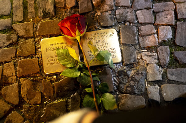 <b>BERLIN — Polished historic markers with a dark legacy:</b> A rose is placed near a fresh polished so-called 'Stolpersteine' or 'stumbling stones' commemorating people, most of them Jews, deported and killed by the Nazis, at the eve of the 85th anniversary of the Nazis' anti-Jewish pogrom in 1938, in Berlin, Germany, Wednesday, Nov. 8, 2023. The stones are among thousands set into sidewalks in front of houses in Germany and other European countries where victims of the Nazis lived or worked before they were deported and killed. The inscriptions include the names of the victims, the dates of their birth and of their deportation and murder. The stones are cleaned by residents on and around the Nov. 9 anniversary to commemorate the victims of Nazi Germany.<br>Photo: Markus Schreiber/AP