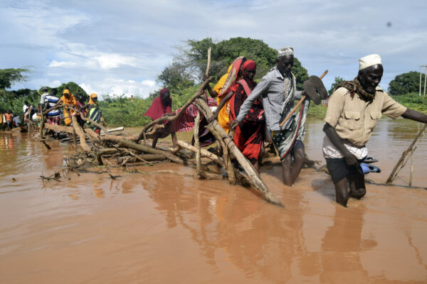 <b>KENYA — Nature’s revenge, as floods displace 36,000 people:</b> Residents of Chamwana Muma village walk through flood water after using a makeshift bridge to cross the swollen River Tana, in Tana Delta, Kenya, on Wednesday, Nov. 15, 2023. Unrelenting rainfall across Kenya’s northern counties and the capital, Nairobi, has led to widespread flooding, displacing an estimated 36,000 people and killing 46 people since the beginning of the rainy season less than a month ago.<br>Photo: Gideon Maundu/AP