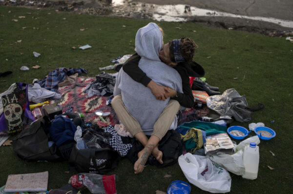 <b>LOS ANGELES — Surviving without a roof over their heads:</b> A homeless couple, who chose not to reveal their names, cuddles amid their possessions in MacArthur Park, Los Angeles, on Friday, Oct. 20, 2023. There is no single reason why Los Angeles became a magnet for homelessness. Two contributing factors: Soaring housing prices and rents punish those with marginal incomes, and a long string of court decisions made it difficult for officials to clear encampments or relocate homeless people from parks and other public spaces.<br>Photo: Jae C. Hong/AP
