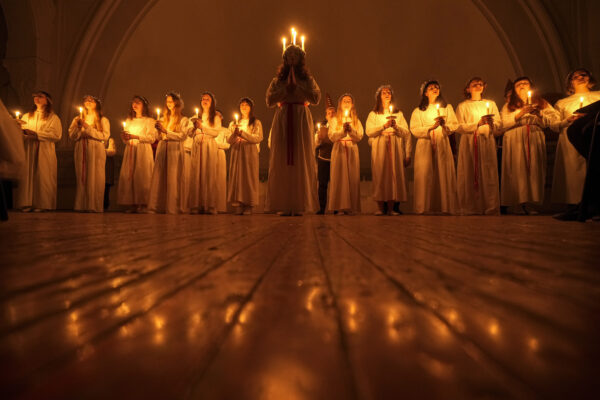 <b>ST. PETERSBURG — A season of celebrations of faith:</b> Young women and men sing carols as they hold candles to celebrate St. Lucia's Day in the Evangelical Lutheran Church of Saint Catherine in St.Petersburg, Russia, Wednesday, Dec. 13, 2023. The Church was built in the 19th century by and for Swedish expatriates in Saint Petersburg, and it is usually called the Swedish church. In the Soviet era, the Church was used as a sports hall. St. Lucia is the patron saint of vision.<br>Photo: Dmitri Lovetsky/AP
