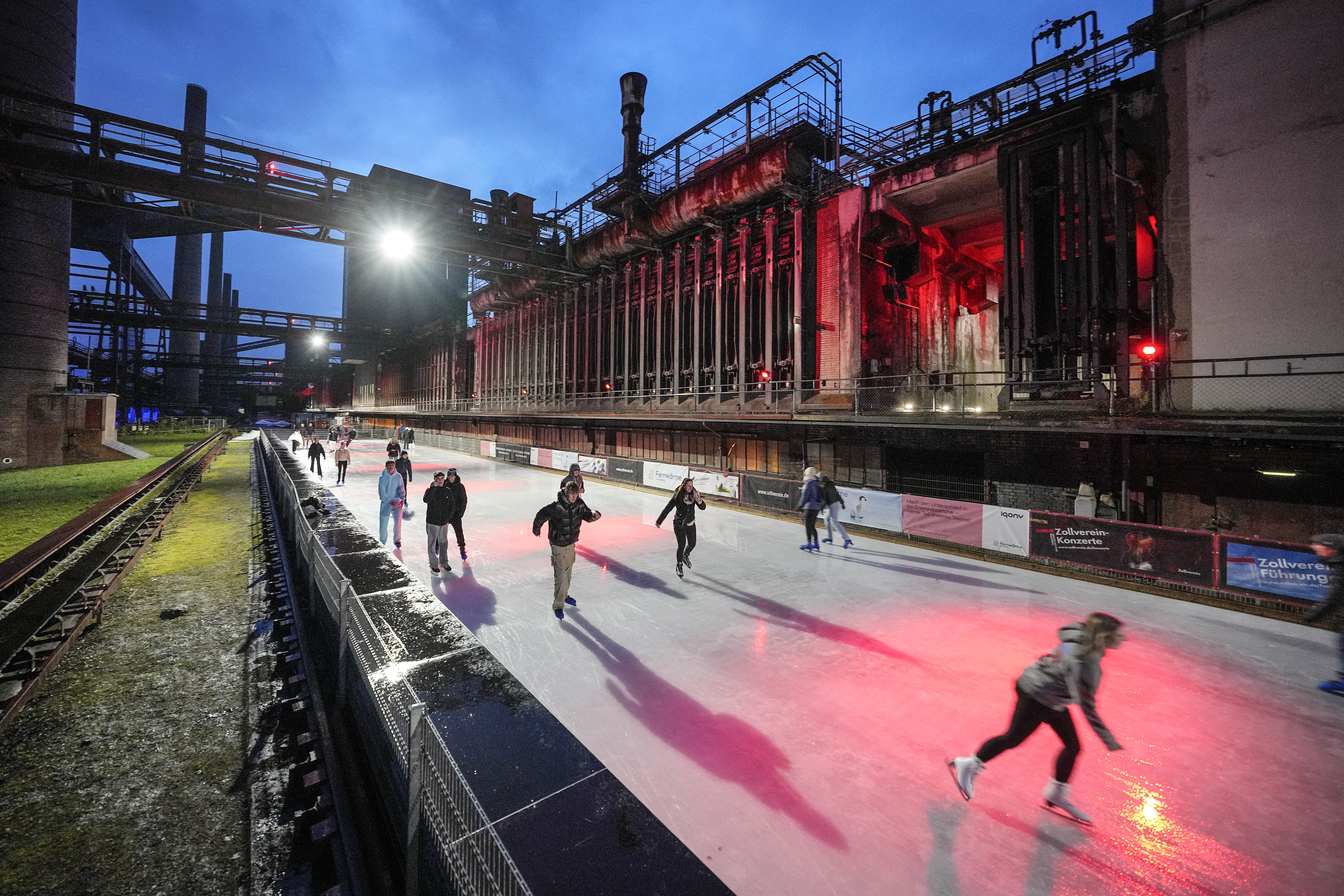 GERMANY — New uses for a former coal refining plant: People skating on ice at the illuminated former coking plant Zollverein in Essen, Germany, Monday, Dec. 11, 2023. The World Heritage site once was the hottest place in town, where coke was made at 1,000 degrees Celsius, now the industrial landmark becomes an ice rink every winter for the citizens.Photo: Martin Meissner/AP