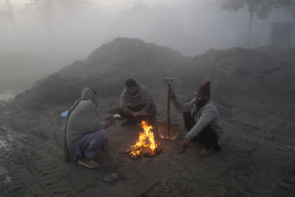 <b>PAKISTAN — Fog, smog and outdoor survival:</b> Laborers warm themselves around a fire while heavy fog envelopes the area in Lahore, Pakistan, Thursday, Dec. 14, 2023. Various cities in eastern and central Pakistan continue to experience heavy fog, disrupting air and road transportation.<br>Photo: K.M. Chaudary/AP