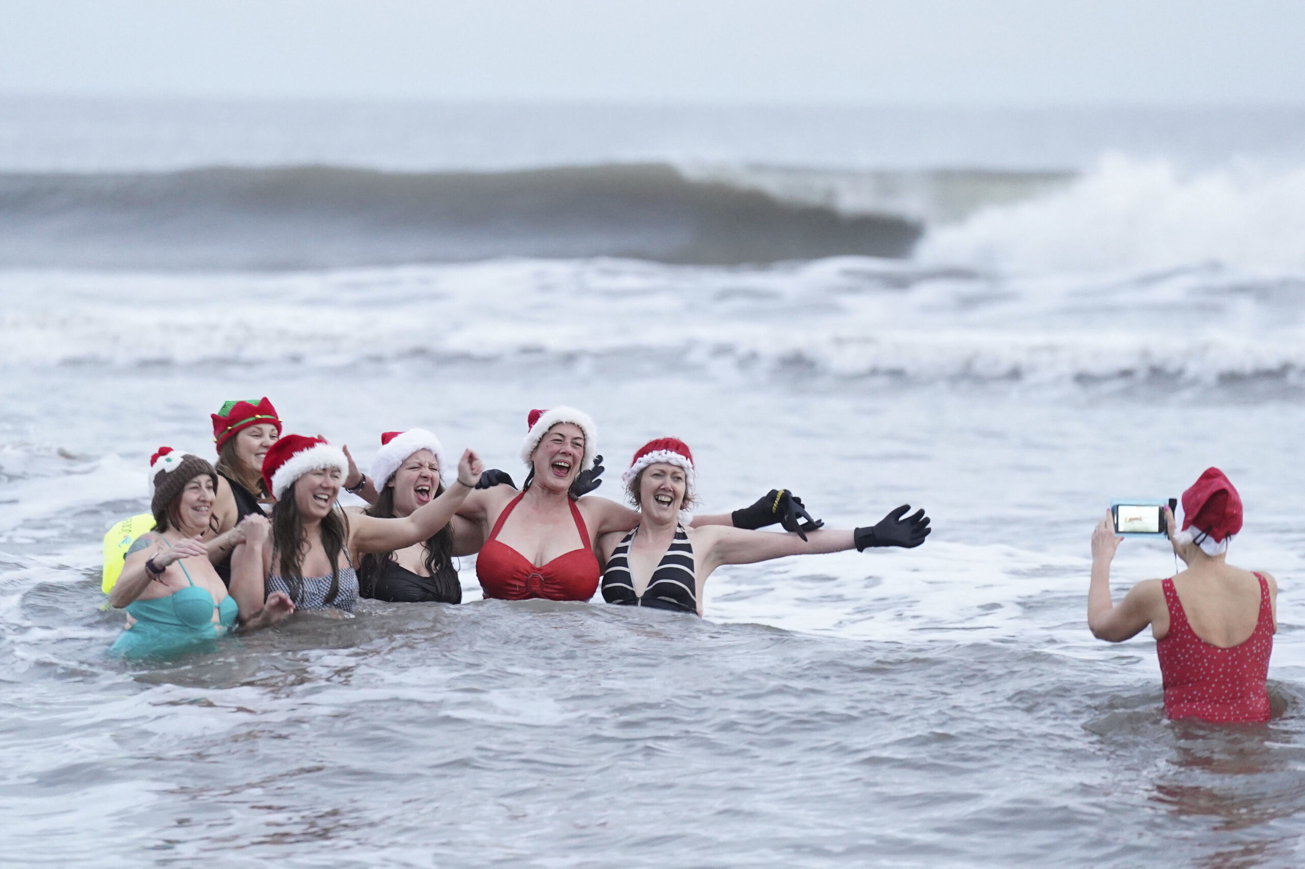 ENGLAND — Like the Coney Island Polar Bear Club, swimming on New Year's Day, these ladies choose Christmas: Swimmers pose for a photo as they take part in the Christmas Day swim at Tynemouth Longsands in the North East of England, Monday, Dec. 25, 2023.Photo: Owen Humphreys/PA via AP