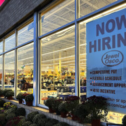 A hiring sign is displayed at a grocery store.