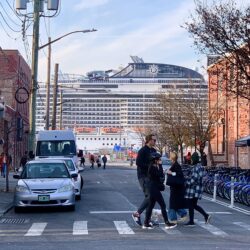 A section of MSC Meraviglia, one of the largest cruise ships in the world, can be seen at the end of the street.