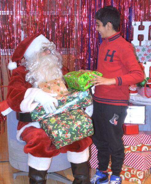 Santa giving a toy to an ecstatic recipient at Maimonides holiday party.