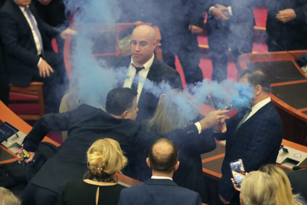 <b>TIRANA — Bodyguard takes one for his boss:</b> Flamur Noka, lawmaker of the Democratic Party points a smoke flare into the face of a bodyguard during a parliament meeting in Tirana, Albania, Thursday, Dec. 21, 2023. Albania's parliament has voted to lift the legal immunity of former Prime Minister Sali Berisha, who leads the opposition Democratic Party and is accused of corruption.<br>Photo: Armando Babani/AP