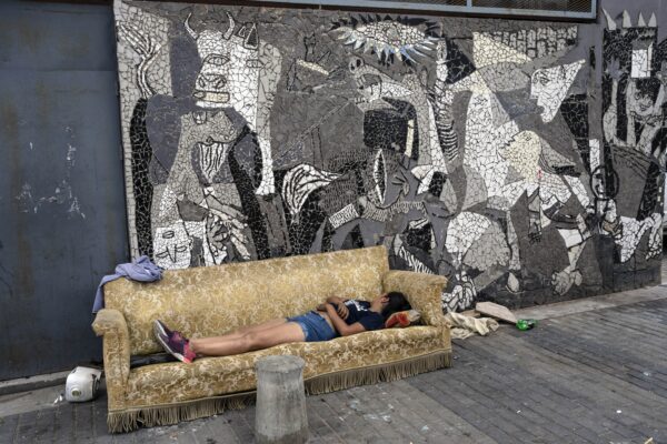 <b>BUENOS AIRES — A fitting Picasso backdrop, a serendipitous sofa in shocking economic conditions:</b> dA woman sleeps on a sofa that was discarded on the sidewalk next to a mural depicting Pablo Picasso's "Guernica" painting in the Padre Carlos Mugica neighborhood of Buenos Aires, Argentina, Thursday, Dec. 14, 2023. Argentina's government cut transportation and energy subsidies and devalued the peso by 50% as part of shock measures new President Javier Milei says are needed to deal with an economic emergency.<br>Photo: Rodrigo Abd/AP