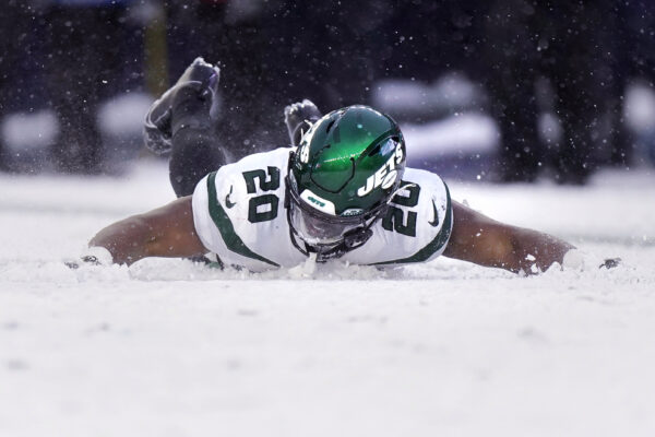 <b>MASSACHUSETTS — ‘Damn! Our first big win and the only place to celebrate is in the snow’:</b> New York Jets running back Breece Hall (20) makes snow angels following his touchdown against the New England Patriots during the second half of an NFL football game, Sunday, Jan. 7, 2024, in Foxborough, Mass. The Jets defeated the Patriots 17-3.<br>Photo: Steven Senne/AP