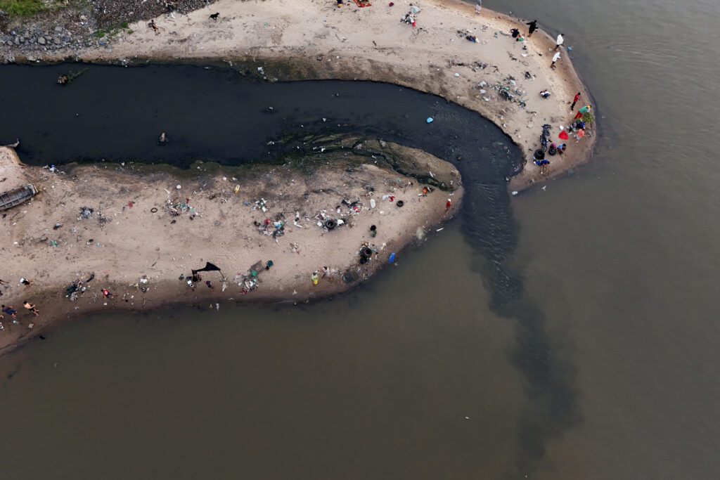 PARAGUAY — Striking overhead view of toxic drainage into a river: People fish next to drainage that flows into the Paraguay River in Asuncion, Paraguay, Sunday, Jan. 28, 2024.Photo: Jorge Saenz/AP