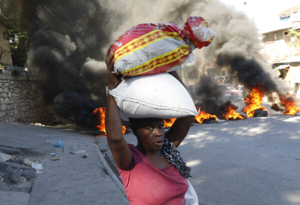 <b>PORT-AU-PRINCE — Pyromaniacal protests:</b> A woman walks past burning tires set on fire by protesters to call attention to the country's insecurity and demanding the resignation of the prime minister, in Port-au-Prince, Haiti, Thursday, Jan. 18, 2024.<br>Photo: Odelyn Joseph/AP