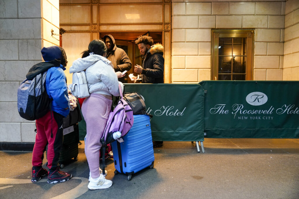An immigrant family shows their paperwork to security guards at the Roosevelt Hotel.