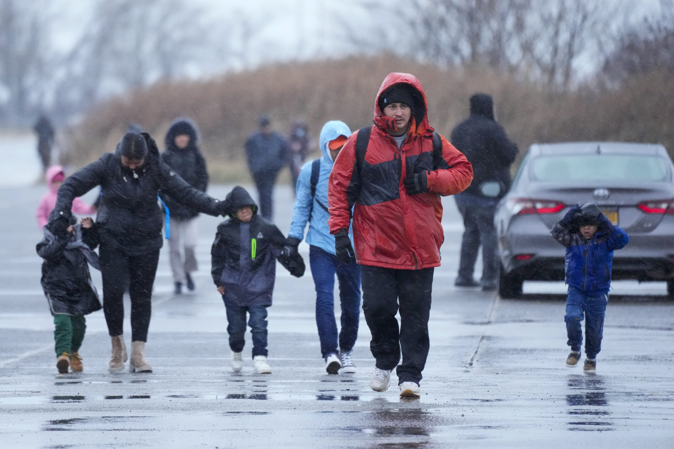 Immigrants run in the rain towards the tents at migrant housing location at Floyd Bennett Field