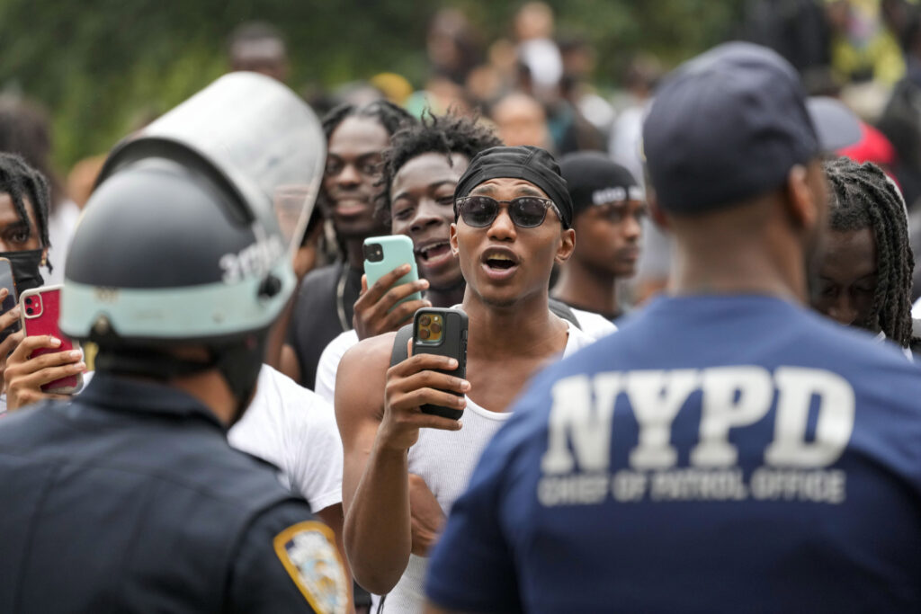 People video New York City Police Department officers as they chant anti-NYPD slogans