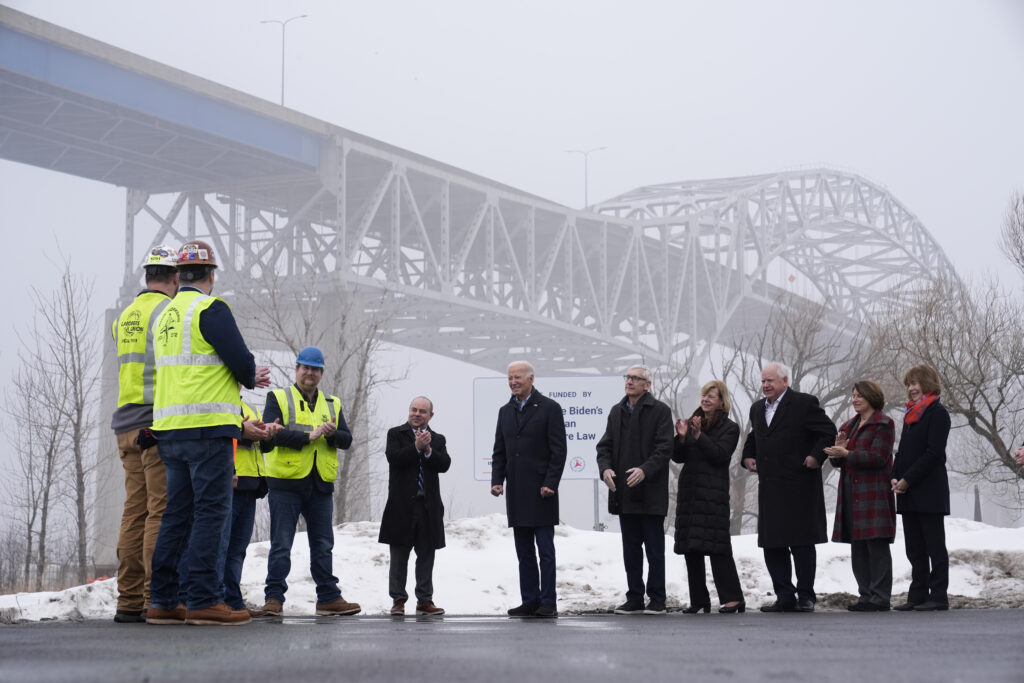 WISCONSIN — Like a piece of iron, the President stands straighter than anyone near him: President Joe Biden speaks with ironworkers and others near the John A. Blatnik Bridge between Duluth, MN, and Superior, WI, Thursday, Jan. 25, 2024, in Superior, WI. Biden is returning to the swing state of Wisconsin to announce $5 billion in federal funding for upgrading the Blatnik Bridge and for dozens of similar infrastructure projects nationwide.Photo: Alex Brandon/AP