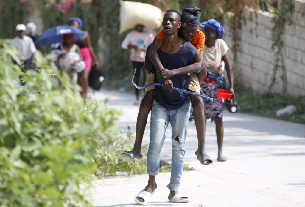 HAITI — Carrying loved ones to safety: A resident carries an elderly man on his back as they flee their home to avoid clashes between armed gangs in the Pernier district of Petion-Ville, Haiti, Wednesday, Jan. 31, 2024.Photo: Odelyn Joseph/AP