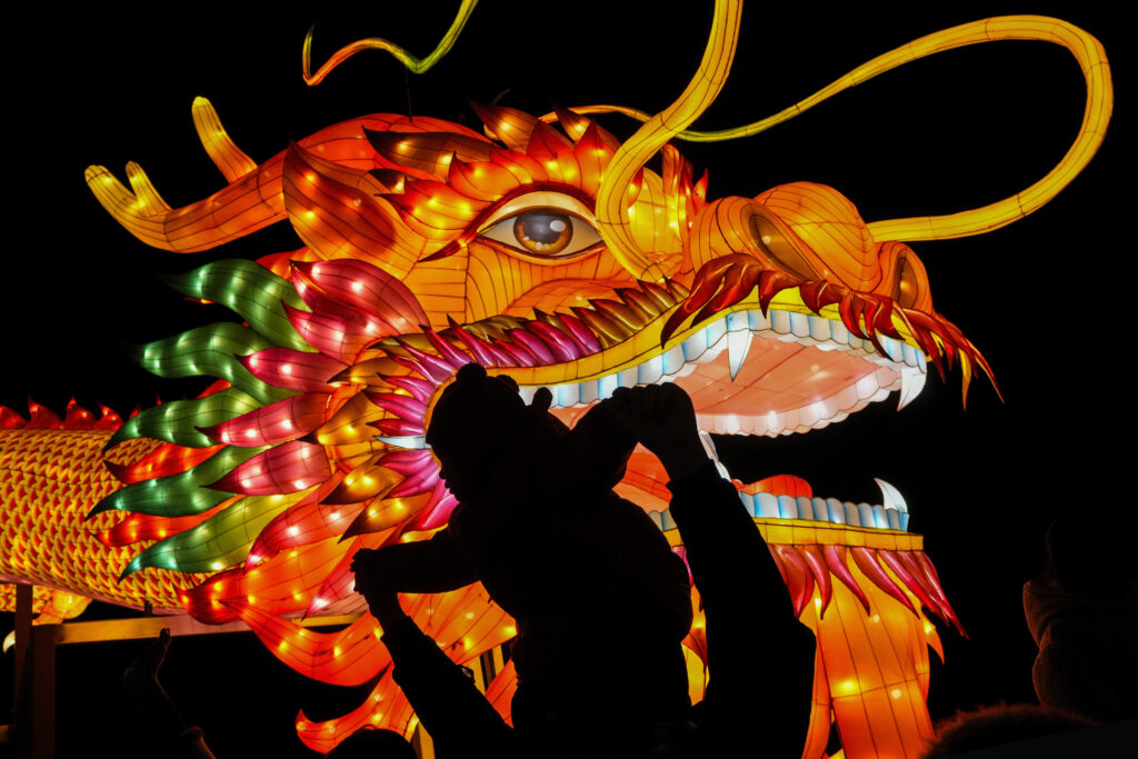 BEIJING — Colorful celebration of dragons: A man and a toddler are silhouetted as they pose for a souvenir photo with a giant dragon lantern decorated near the popular Houhai Lake in Beijing, Thursday, Feb. 8, 2024. Chinese will celebrate Lunar New Year on Feb. 10 this year, which marks the Year of the Dragon on the Chinese zodiac.Photo: Andy Wong/AP