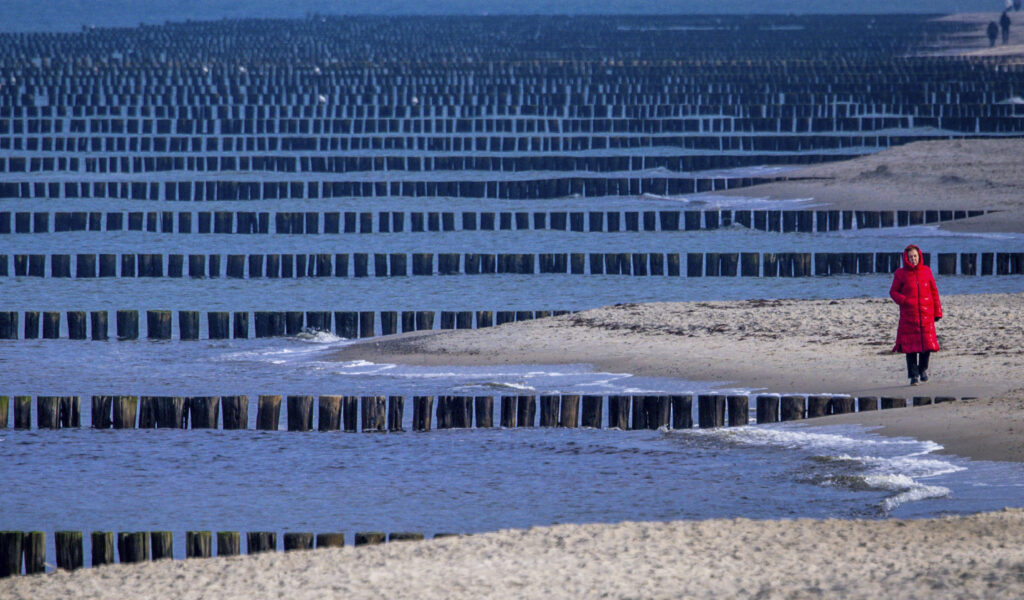 GERMANY — Like protective jetties on the south shore of Long Island, Germany has buried posts called groynes: A woman walks on the Baltic Sea beach with its numerous rows of groynes, in Graal-Müritz, Germany, Wednesday, Feb. 28, 2024.Photo: Jens Büttner/dpa via AP