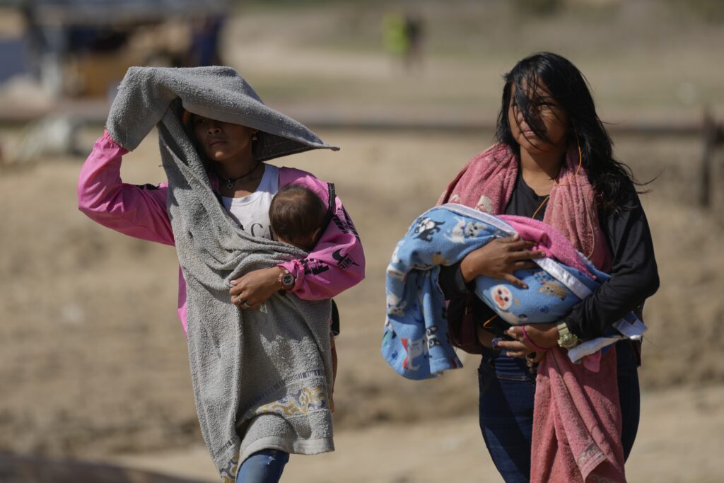 VENEZUELA — Illustrating full impact on families: Women carry babies after arriving by boat from La Bulla Loca mine, which collapsed, in La Paragua, Bolivar state, Venezuela, Friday, Feb. 23, 2024. The collapse of the illegally operated open-pit gold mine in a remote area of central Venezuela killed at least 16 people.Photo: Ariana Cubillos/AP