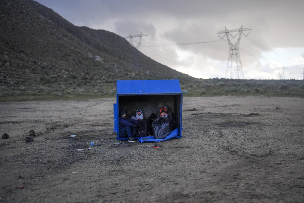 CALIFORNIA — The road to a different life takes a lot of stops and stalls: Asylum-seeking migrants from Peru and Ecuador take shelter from the wind and rain as they wait to be processed in a makeshift, mountainous campsite after crossing the border of Mexico Friday, Feb. 2, 2024, near Jacumba Hot Springs, CA.Photo: Gregory Bull/AP