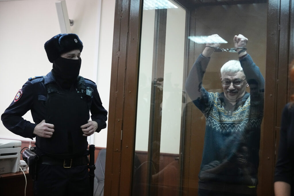 MOSCOW — This is where enforcers get to cover their faces: The co-chair of the Nobel Peace Prize-winning Memorial Human Rights Centre, Oleg Orlov, gestures while standing in a glass cage after he was taken into custody in the courtroom during a court session for a new trial on charges of repeated discrediting Russian military, in Moscow, Russia, on Tuesday, Feb. 27, 2024.Photo: Alexander Zemlianichenko/AP
