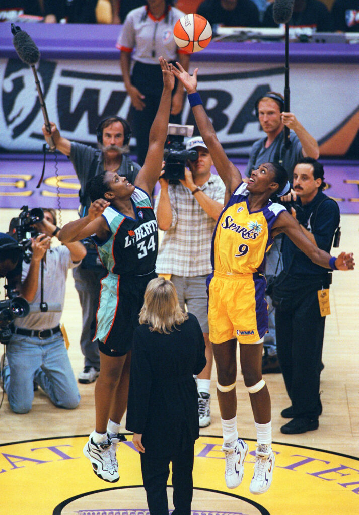 In this June 21, 1997, file photo, Los Angeles Sparks' Lisa Leslie (9), right, and New York Liberty's Kym Hampton (34) leap for the ball during the opening tip of the inaugural WNBA basketball at the Forum in Inglewood, Calif.