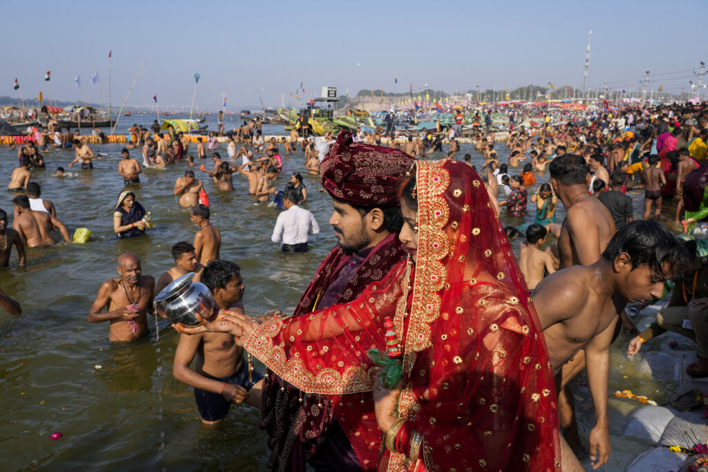 INDIA — A fact of life here — human interaction with the Ganges: A newly married couple offer prayers as Hindu devotees take a dip at the Sangam, the meeting point of the Ganges and the Yamuna rivers, during Shivaratri festival in Prayagraj, India, Friday, March 8, 2024.Photo: Rajesh Kumar Singh/AP
