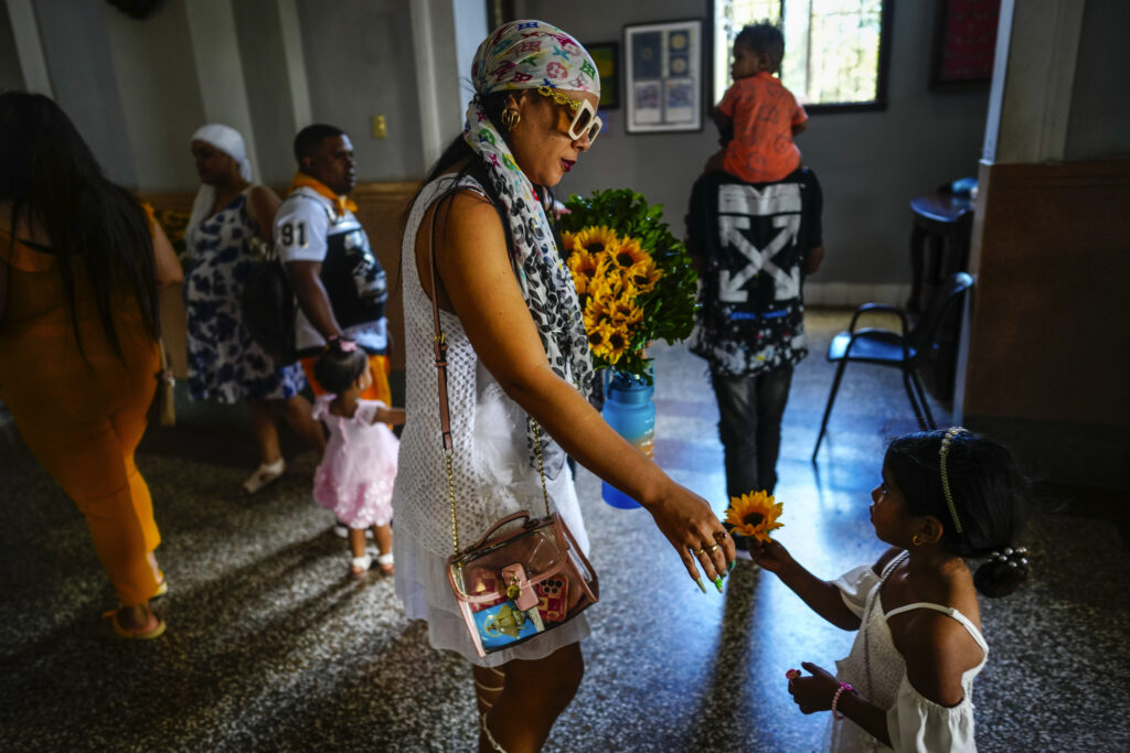 CUBA — Sunflower as sacred unification tool with Cubans who were exiled or immigrated: A mother and daughter prepare to make an offering of sunflowers to the Virgin of Charity of Cobre at her shrine in El Cobre, Cuba, on Sunday, Feb. 11, 2024. The Vatican-recognized Virgin, venerated by Catholics and followers of Afro-Cuban Santeria traditions, is at the heart of Cuban identity, uniting compatriots from the Communist-run Caribbean island to those who were exiled or emigrated to the U.S.Photo: Ramon Espinosa/AP