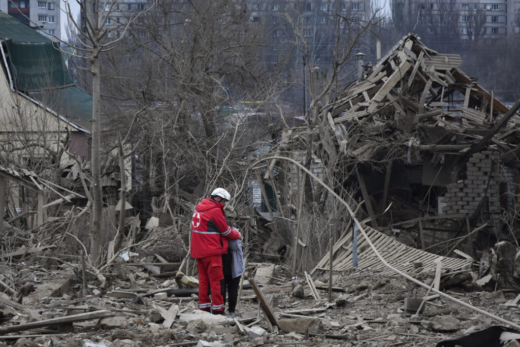 UKRAINE — Brightly colored jacket contrasts with grim, drab scene of destruction: A medical worker comforts a woman at the site of Russia's air attack, in Zaporizhzhia, Ukraine, Friday, March 22, 2024.Photo: Andriy Andriyenko/AP