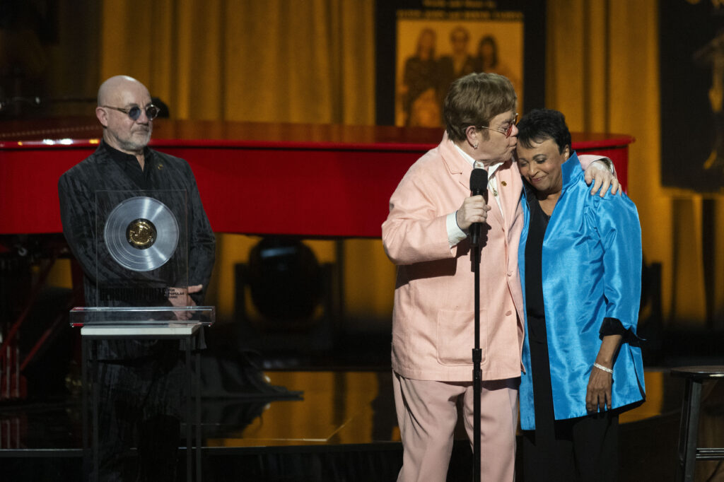 WASHINGTON, DC — A special kiss for the lady who ‘lays the yellow brick road’ on the path to knowledge: Elton John gives a kiss to Librarian of Congress Carla Hayden, right, after being awarded the Gershwin Prize with fellow honoree Bernie Taupin, left, during the 2024 Library of Congress Gershwin Prize for Popular Song tribute concert honoring John and Taupin at DAR Constitution Hall on Wednesday, March 20, 2024, in Washington.Photo: Kevin Wolf/AP