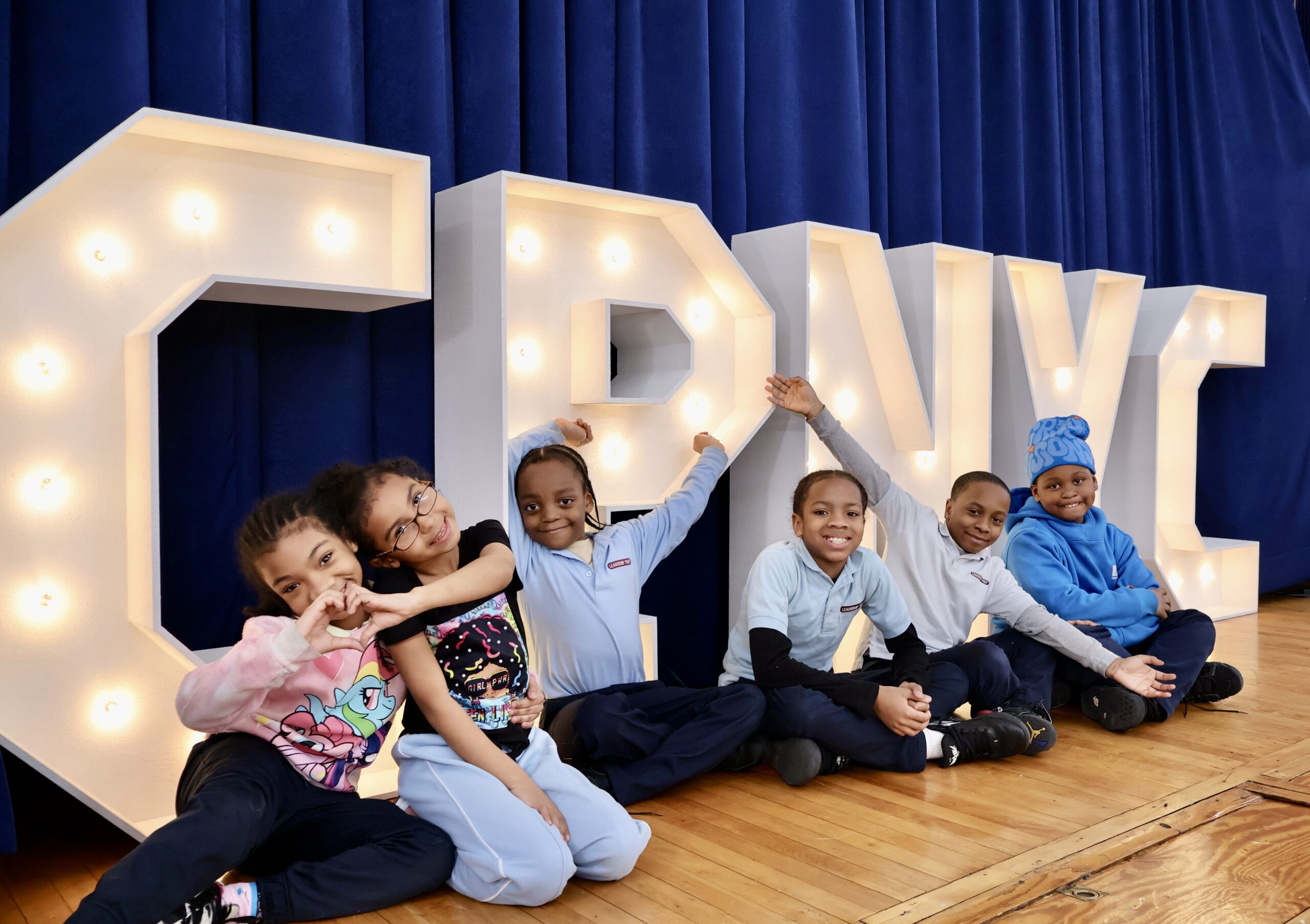 Children gather in front of the Children of Promise, NYC sign, showcasing the organization dedicated to supporting those affected by parental incarceration, now bolstered by a $2 million grant from MacKenzie Scott’s Yield Giving.Photo courtesy of CPNYC