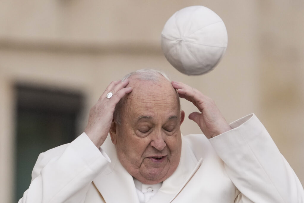 VATICAN — ‘Quick … we need a bobby pin …’: Pope Francis tries to catch his cap as wind blows it away while arriving for his weekly general audience in St. Peter’s Square at the Vatican, Wednesday, March 13, 2024.Photo: Andrew Medichini/AP
