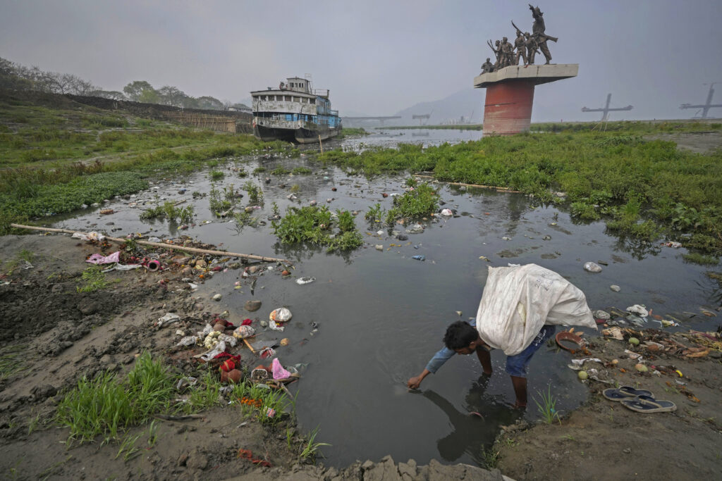 INDIA — Even on World Water Day, stagnant, polluted puddles yield treasures for recyclers: A ragpicker looks for recyclable material in the polluted waters on the banks of Brahmaputra river on World Water Day in Guwahati, India, Friday, March 22, 2024.Photo: Anupam Nath/AP