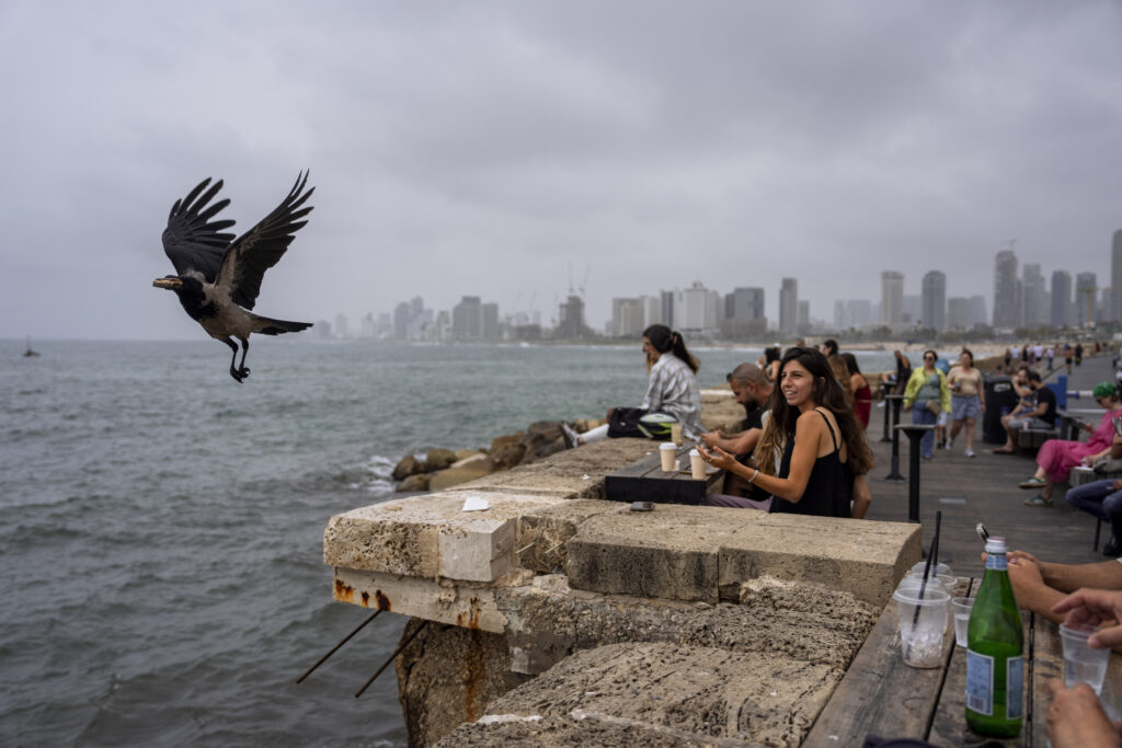 People sit in a bar overlooking the Mediterranean Sea at the old port of Jaffa, a mixed Jewish-Arab part of Tel Aviv, Israel, Friday, April 26, 2024. (AP Photo/Oded Balilty)