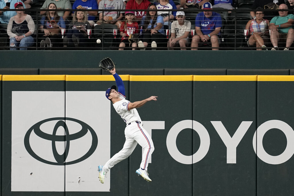 Texas Rangers left fielder Wyatt Langford makes a leaping catch on a fly out by Seattle Mariners' Mitch Haniger in the first inning of a baseball game in Arlington, Texas, Thursday, April 25, 2024. (AP Photo/Tony Gutierrez)