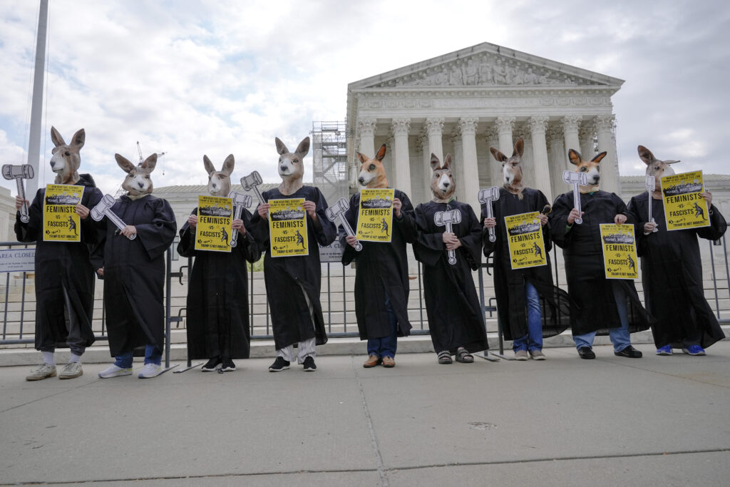 Demonstrators stand outside the Supreme Court as the justices prepare to hear arguments over whether Donald Trump is immune from prosecution in a case charging him with plotting to overturn the results of the 2020 presidential election, on Capitol Hill Thursday, April 25, 2024, in Washington. (AP Photo/Mariam Zuhaib)