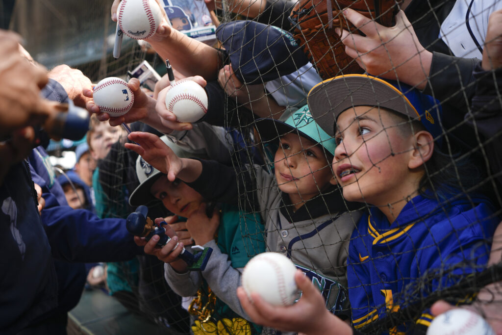 Fans vie for an autograph from Seattle Mariners center fielder Julio Rodríguez before a baseball game between the Mariners and the Cleveland Guardians, Wednesday, April 3, 2024, in Seattle. (AP Photo/Lindsey Wasson)