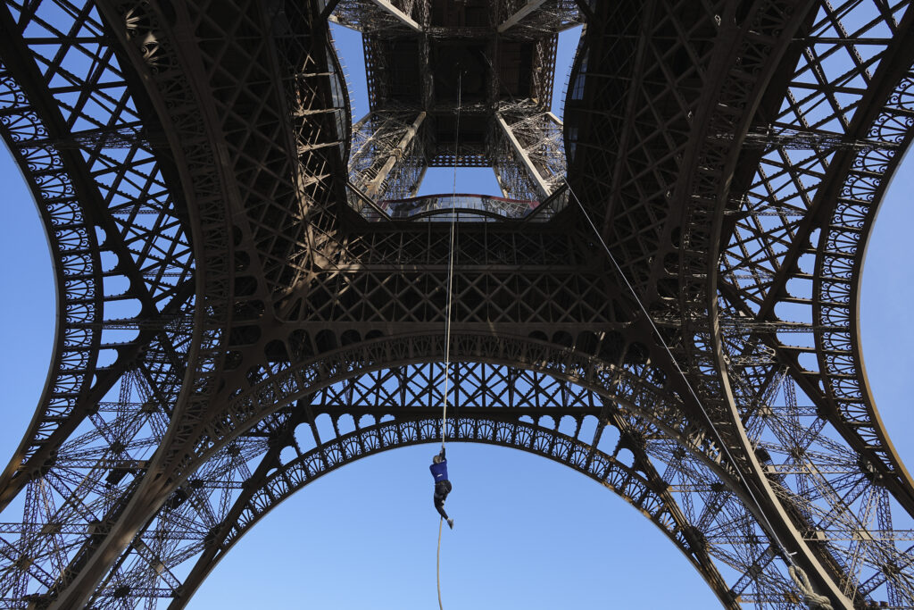 Anouk Garnier ascends by rope under the Eiffel Tower during an attempt to beat a record for climbing up a rope, Wednesday, April 10, 2024 in Paris. Anouk Garnier successfully climbed up the 110 meters (361 feet) from the ground to the second story of the tower. (AP Photo/Laurent Cipriani)
