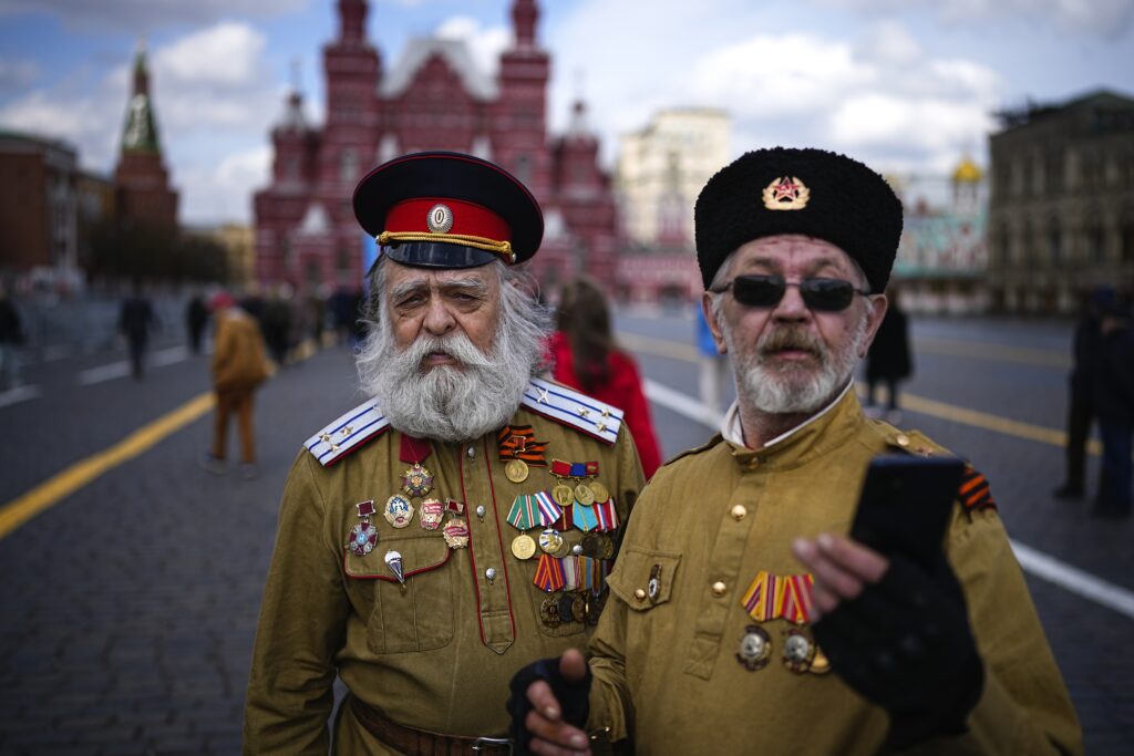 Two men in Russian Cossack uniforms pose for a selfie after visiting the Mausoleum of the Soviet founder Vladimir Lenin marking the 154th anniversary of his birth in Red Square, with the Historical Museum in the background in Moscow, Russia, Monday, April 22, 2024. (AP Photo/Alexander Zemlianichenko)