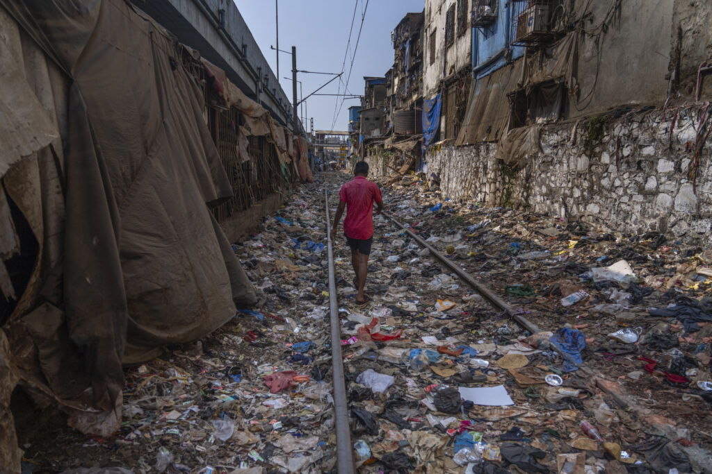 A man walks on a railway track littered with plastic and other waste materials on Earth Day in Mumbai, India, Monday, April 22, 2024. This year’s Earth Day is focusing on the threat that plastics pose to our environment. (AP Photo/Rafiq Maqbool)