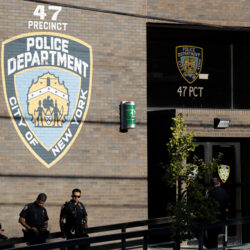 Police officers stand in front of the 47th precinct.