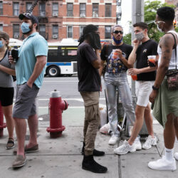 People gather on a street in the Hell's Kitchen neighborhood of New York while waiting to get takeout drinks at a bar, May 29, 2020.