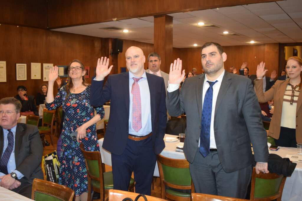 The newly ratified officers of the KCCBA stand among the audience, right hands raised, as they take their oath, committing to their roles and responsibilities in the association at KCCBA CLA on Federal Crimes.