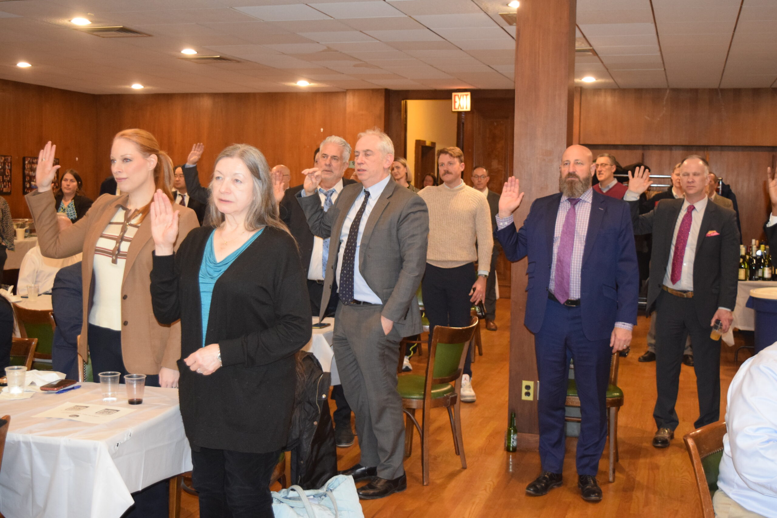 Members of the Board of Directors stand in the audience with their right hands raised, participating in the swearing-in ceremony officiated by Judge Espinal at KCCBA CLA on Federal Crimes.
