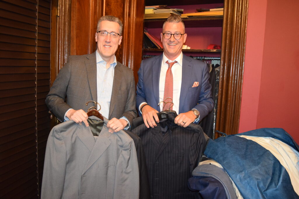 Michael Farkas (left) and Darran Winslow, president of the Kings County Criminal Bar Association, pose in front of the closet of over 50 suits they already collected. Brooklyn Eagle photo by Robert Abruzzese