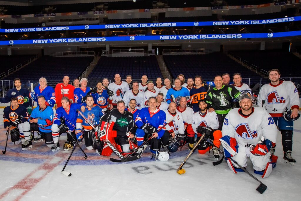 Players from both teams gather for a group photo, celebrating their return to the charity match at UBS Arena at Tunnel to Towers hockey game.