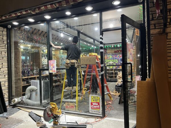A worker installs the new bulletproof plexiglass partitions inside the Exotic Smoke shop after robbers smashed glass cases inside the shop.
