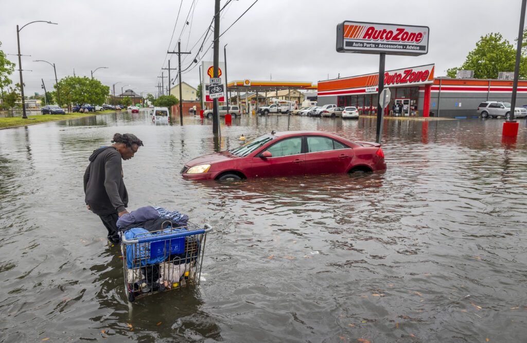 People carry their belongings down a flooded Broad Street in New Orleans, during a severe rainstorm on Wednesday, April 10, 2024. (Chris Granger/The Times-Picayune/The New Orleans Advocate via AP)