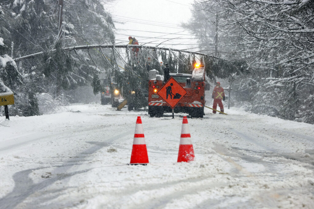 A portion of Route 9 between Falmouth and Cumberland is closed as crews work to remove a downed tree spanning the snow-covered roadway in Falmouth, Maine, Thursday, April 4, 2024, following a spring snowstorm. (Ben McCanna/Portland Press Herald via AP)